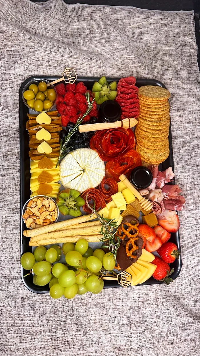 Charola rectangular con queso brie, rosas de salami, frutos rojos, kiwi, uvas, galletas, nueces y miel