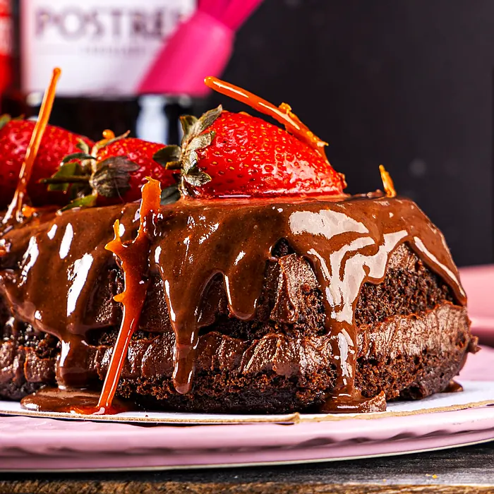 Acercamiento a un pastel de chocolate con relleno cremoso, fresas y caramelo