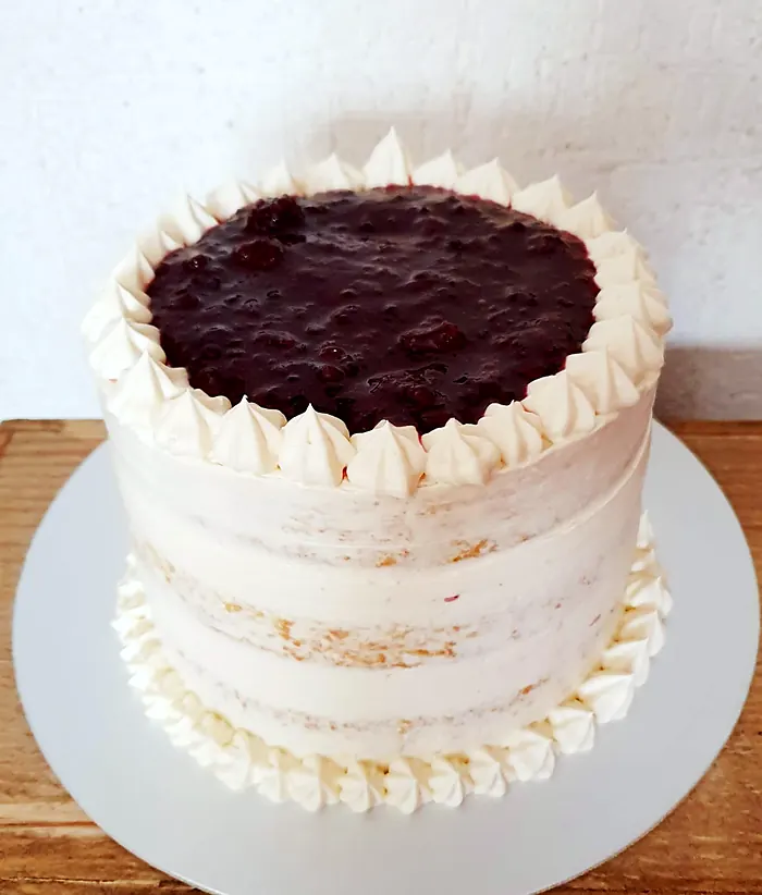 Pastel blanco con merengue y cobertura de frutos rojos